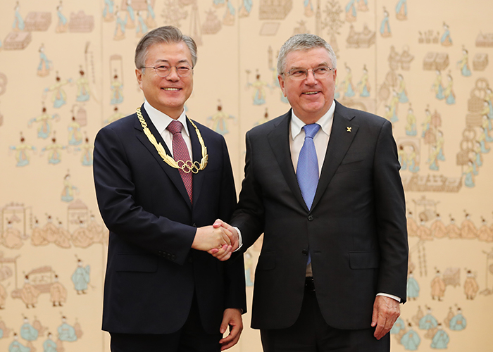President Moon (left) shakes hands with Thomas Bach, president of the International Olympic Committee, after the receiving the Olympic Order in Gold, at Cheong Wa Dae on Aug. 30. (Yonhap News)